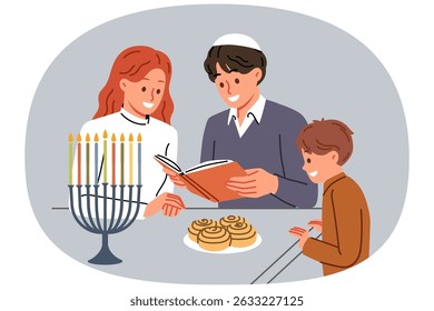 A família judia celebra o dia do Chanucá e lê o livro sagrado juntos, de pé perto da mesa e de menores. Mãe e pai judeus leem enciclopédia para filho pequeno, falando sobre tradições do povo de israel