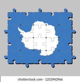 Jigsaw puzzle of Antarctica flag in a plain white map of the continent on a blue background. Concept of Fulfillment or perfection.
