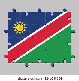 Jigsaw puzzle of Namibia flag in a white-edged red diagonal band and triangle is blue, with a gold sun and the lower triangle is green. Concept of Fulfillment or perfection.