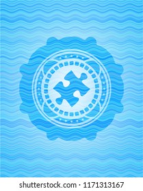 jigsaw puzzle piece icon inside light blue water wave badge.