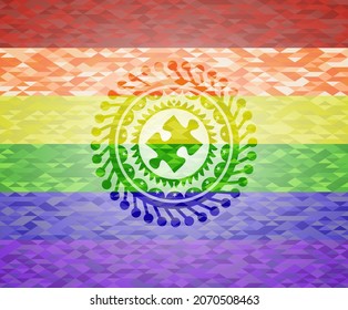 icono de la pieza del rompecabezas dentro del emblema sobre el fondo de mosaico con los colores de la bandera LGBT. 
