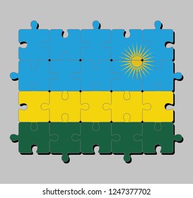 Jigsaw puzzle of Rwanda flag in a horizontal tricolor of blue yellow and green with a yellow sun.
