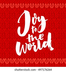 Joy to the world. Christmas greeting card with brush calligraphy. Handwriting on red knitted background.