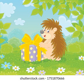 Joyful and friendly smiling little hedgehog holding a beautiful box with a holiday gift on a pretty glade of a green forest on a warm summer day, vector cartoon illustration