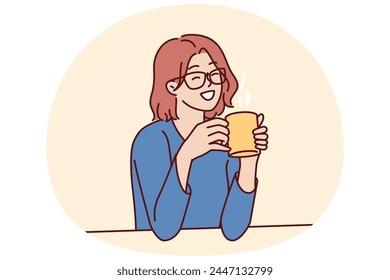 Joyful woman holding coffee mug sitting at table and smiling remembering happy moments from life during lunch break. Girl in casual clothes drinks hot tea or coffee to gain vigor and energy