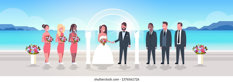 just married bride and groom with bridesmaids groomsmen standing together on sea beach near arch wedding ceremony concept sunrise mountains background full length horizontal