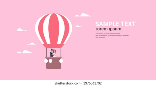 just married bridegroom and bride flying in air balloon romantic couple man woman in love wedding day concept pink background copy space full length horizontal flat