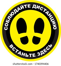 Mantén la distancia aquí en señal rusa. Marca del suelo pegatina de impresión de distanciamiento social con huella en círculo amarillo y texto blanco. Ver administración de cola coronavirus Covid-19
