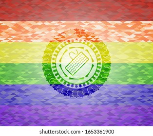 icono del teclado dentro del emblema sobre fondo de mosaico con los colores de la bandera LGBT