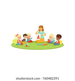 Kids sitting on carpet with teacher and learning to pronounce letter A. Speech therapist teach little boys and girls in playful form