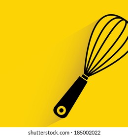 kitchen whisk on yellow background, cooking concept