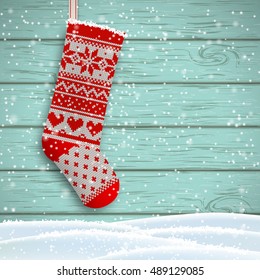 knitted christmas stocking with red patterns on blue wooden background, vector illustration, eps 10 with transparency and gradiennt meshes