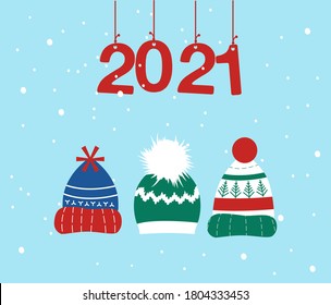 Knitted headwear collection,cosy scandinavian winter hats and caps.Happy New Year 2021 and Christmas postcard.Numbers are hanging on ribbons, it is snowing.Childish accessory with pom poms,snowflakes