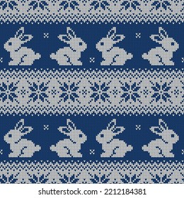 Knitted seamless pattern for 2023 new year of the rabbit. Vector background with cute bunnies and scandinavian ornaments. Dark blue and white sweater print.