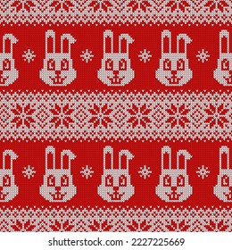 Knitted seamless pattern for 2023 new year of the rabbit. Vector background with cute bunnies, snowflakes and scandinavian ornaments. Red and white sweater print.