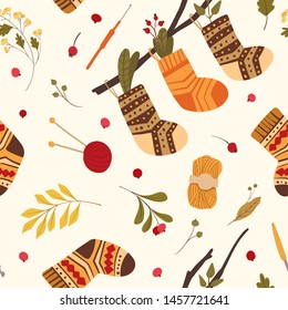 Knitted woolen socks flat vector seamless pattern. Warm winter footwear with folk ornaments hanging on tree branch. Autumn leaves, dogrose hips, guelder berries. Wallpaper, wrapping paper design