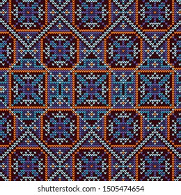 Knitting pattern with the image of snowy flowers. Blue flowers with geometric ornament on a dark background.
