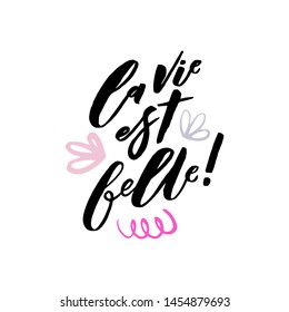 La vie est belle. Life is beautiful in french. Art for social media and apparel. Hand drawn brush lettering with decorative elements. Inspirational quote. Ready-to-use design. Vector illustration.