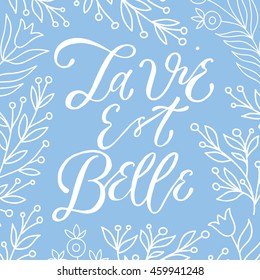 la vie est belle life is beautiful lettering  poster with floral branches, typography poster, hand calligraphy, calligraphy positive phrase on a blue background