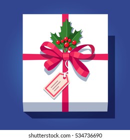 Labeled white wrapped gift box decorated with red ribbon bow, ilex plant sprig with leafs and berries. Flat style vector illustration isolated on blue background.