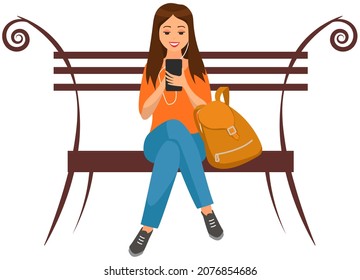 Lady with backpack sits on bench, chatting, communicating using electronic device. Woman talking by phone on bench. Girl uses modern technology to communicate. Girl in headphones sits with smartphone