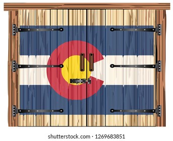A large closed wooden barn double door with bolt and hinges and the Colorado flag painted on