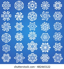 Large collection of delicate intricate white snowflake designs on a cool blue background symbolic of winter and the Christmas holiday season