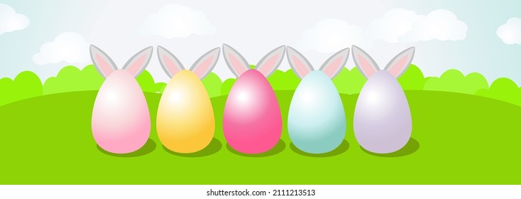 Große bemalte Eier stehen auf dem grünen Gras und die Ohren des Osterhasen tauchen von hinten heraus. Ein langes horizontales Banner, das einen schönen Frühlingstag, ein grünes Feld oder eine Wiese und einen blauen Himmel darstellt