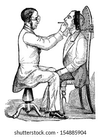 Laryngoscopy, showing a doctor looking into a patient's mouth, illuminated by indirect light from a gas lamp, vintage engraved illustration. Usual Medicine Dictionary by Dr Labarthe - 1885