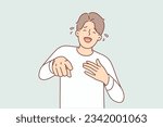 Laughing man pointing fingers at screen after hearing funny joke from buddy and nicker over funny joke. Laughing young guy with tears in eyes having fun due to participating in prank.