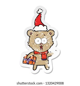 laughing teddy  bear with christmas present wearing santa hat