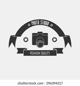 The layout for the studio logo in vintage style with a camera and tapes. On the tape the inscription: "Photo Studio" and "premium quality". Can be used to design business cards, posters, posters