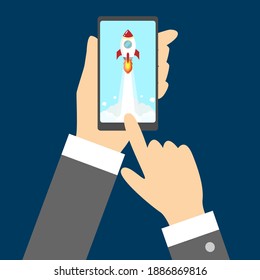left hand holding mobile phone right hand touching screen showing rocket launching to the sky. start up technology business concept
