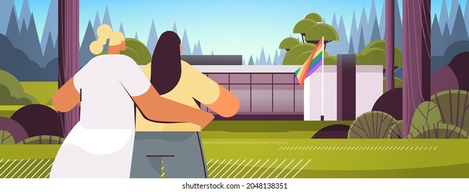 lesbian couple hugging and looking at new modular house with rainbow flag transgender love LGBT community