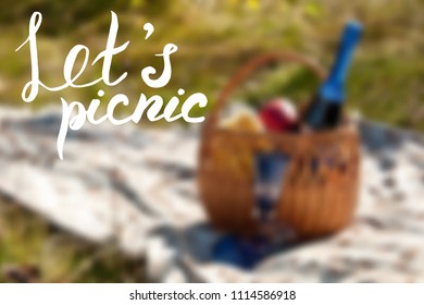 Let's picnic poster. Lettering on blurred background with picnic basket. Vector illustration
