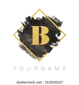 Letter B logo design. Black watercolor brush stroke with gold letter and gold square frame.