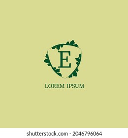 Plantilla de diseño del logotipo alfabético de la letra E aislada en color beige verde. Ilustración decorativa del blindaje floral. Guardia de la Naturaleza, concepto del logotipo de Seguridad. 