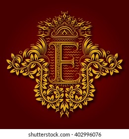 Letter E heraldic monogram in coats of arms form. Vintage golden logo with shadow on maroon background. Letter E is surrounded by floral elements of design.