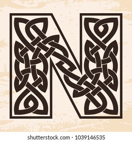 Letter of the English alphabet with Celtic national ornament as interlaced ribbon on a beige background. Paryrus with the aging effect.