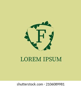 Letter F alphabetic logo design template isolated on green beige color. Nature Guard, Security logo concept. Decorative floral shield sign illustration. 