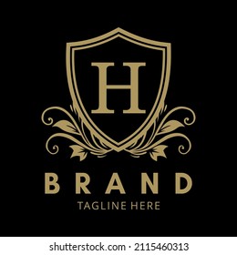letter H in the gold shield logo