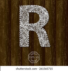 Letter R, made with threads on pins on wooden background. Part of collection.