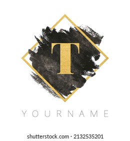 Letter T logo design. Black watercolor brush stroke with gold letter and gold square frame.