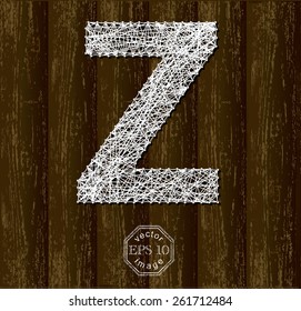 Letter Z, made with threads on pins on wooden background. Part of collection.