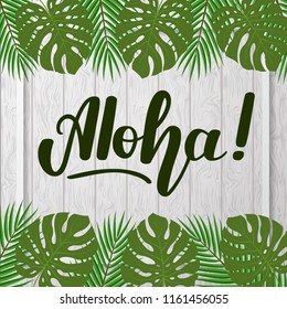 Lettering "Aloha" on gray wooden background with tropical leaves.