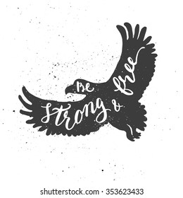 Lettering composition. Phrase Be strong & free inscribed into eagle silhouette. Ink splashes on white background.