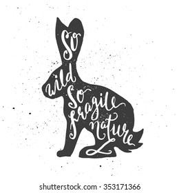 Lettering composition. Phrase So wild so fragile nature inscribed into tolai hare silhouette. Ink splashes on white background.