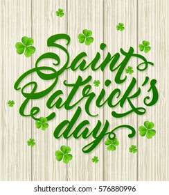 Lettering and green clover leaves on a wooden background. Greeting card for St. Patrick's Day