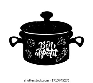 Lettering of phrase Bon Appetit on black pan with vegetables. Hand drawn typography poster. Inspirational vector typography. Vector calligraphy and pan illustration.