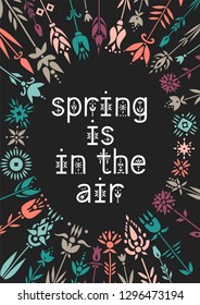 Lettering poster Spring Is In The Air inside the floral wreath on a black background.